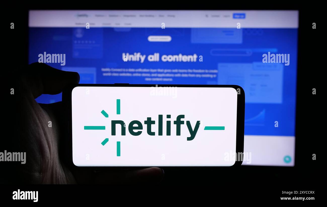 Personne tenant le téléphone portable avec le logo de la société de plate-forme de développement Web des États-Unis Netlify Inc. devant la page Web d'affaires. Concentrez-vous sur l'affichage du téléphone. Banque D'Images