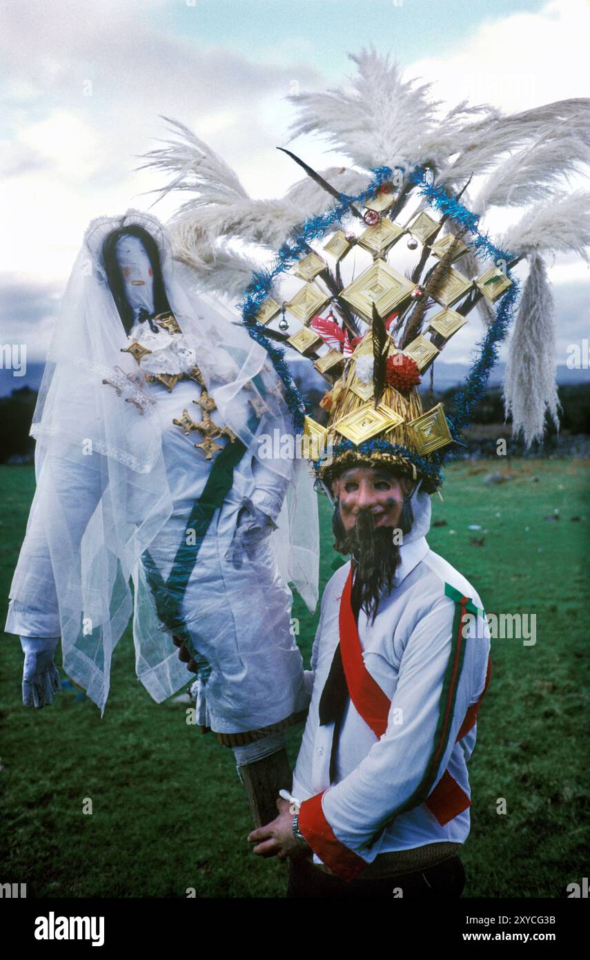 Un garçon Biddy à l'effigie de St Brigid connu sous le nom de Biddy qui est porté en procession d'une visite de maison à l'autre. Il est déguisé et porte la traditionnelle coiffe de paille conique haute qui incorpore les croix traditionnelles de St Brigit en paille. Les Biddy Boys à Killorglin célèbrent la Sainte Brigit ou Brigid celtique, qui était une déesse païenne de l'Irlande pré-chrétienne. Le 1er février est son jour des Saints. Killorglin, comté de Kerry, Irlande du Sud février 1972 1970 Eire HOMER SYKES Banque D'Images