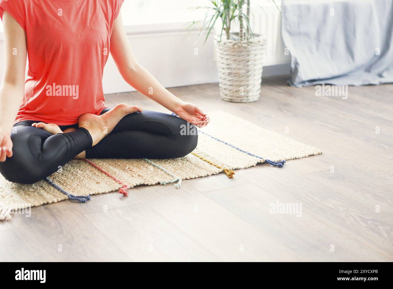 Jolie jeune femme brune de l'exercice et assis en position du lotus yoga tout en se reposant à la maison Banque D'Images