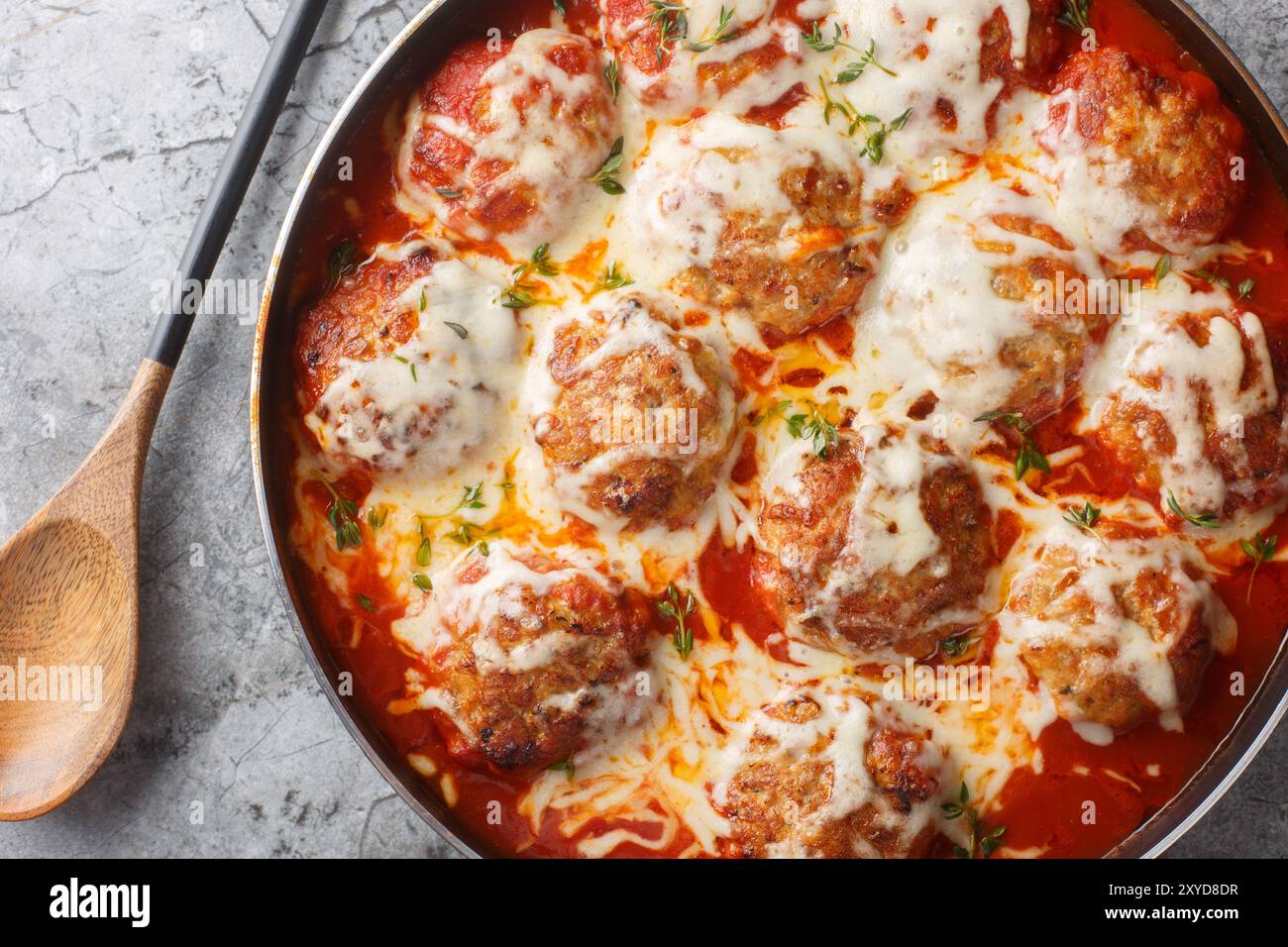 Gratin de boulettes de viande dans une sauce tomate avec du fromage mozzarella et du parmesan gros plan dans une poêle sur la table. Vue horizontale de dessus Banque D'Images