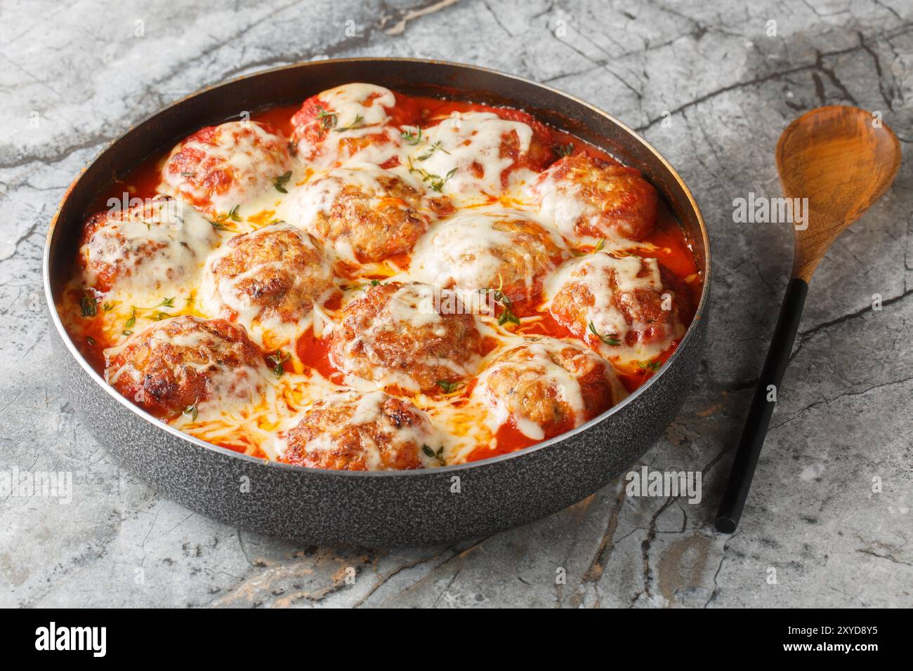 Casserole italienne de boulettes de viande cuites au four dans une sauce tomate épicée avec fromage mozzarella et thym gros plan dans un plat de cuisson sur la table. Horizontal Banque D'Images