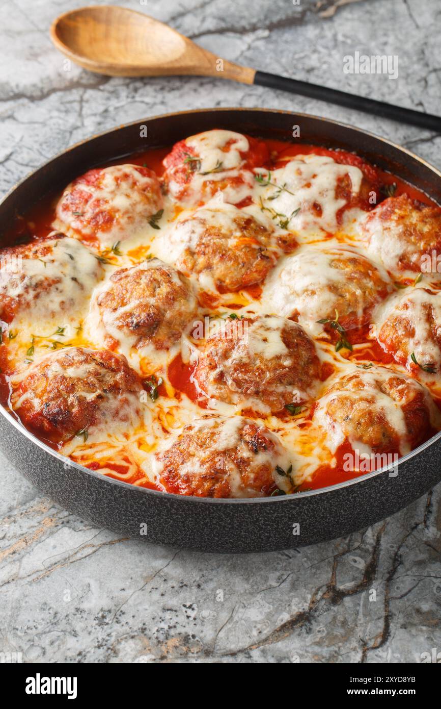 Boulettes de viande cuites dans une sauce tomate avec du fromage mozzarella et du thym gros plan dans un plat allant au four sur la table. Vertical Banque D'Images