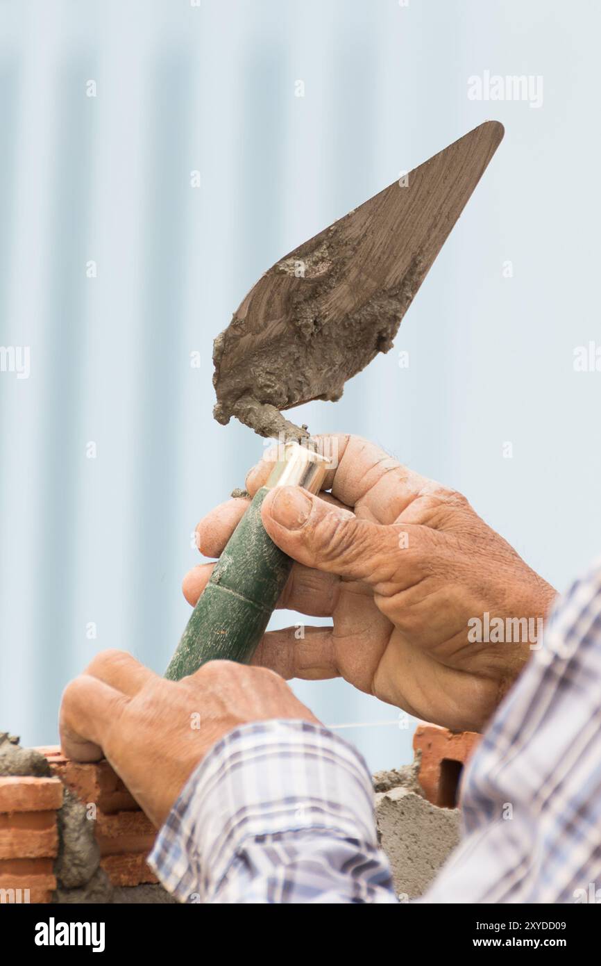 Charpentier travaillant dans la construction site d'un mur de briques. Charpentier de poser une autre rangée de briques dans le site Banque D'Images