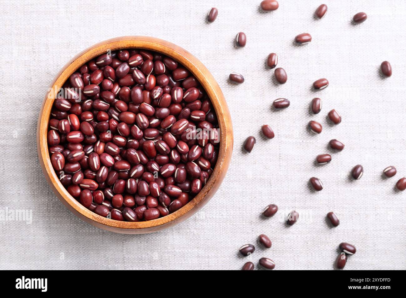 Haricots Adzuki dans un bol en bois sur tissu de lin. Aussi connu sous le nom azuki, aduki, rouge ou rouge haricot mung. Graines séchées de Vigna angularis. Banque D'Images
