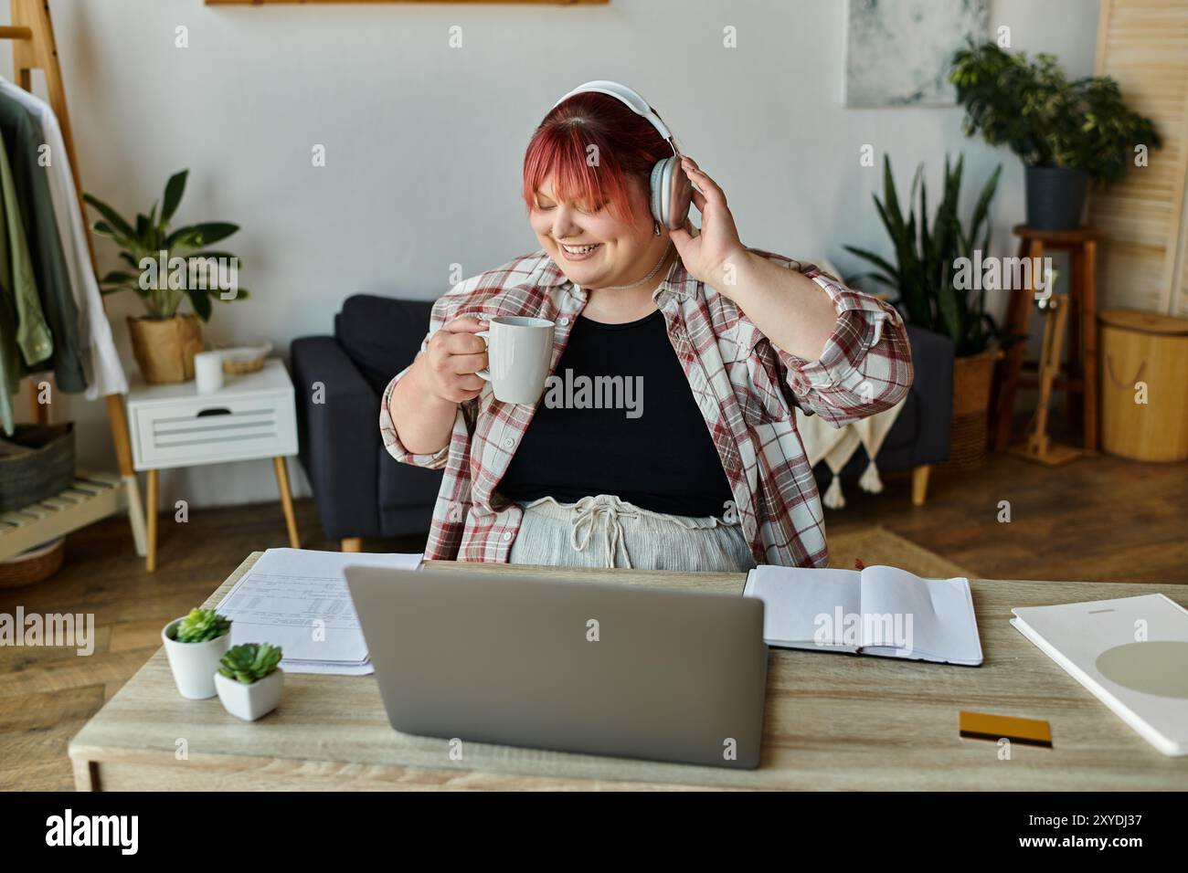 Une femme aime une tasse de café et de musique tout en travaillant à la maison. Banque D'Images