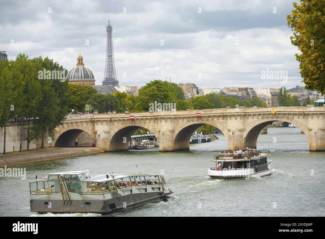 Un beau paysage urbain incluant la Tour Eiffel au loin avec des bateaux de croisière passant le pont neuf sur la Seine à Paris, France, Europe Banque D'Images