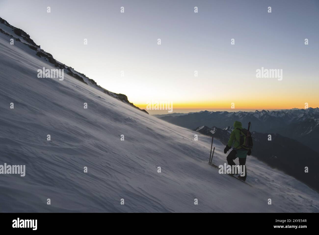 L'alpiniste professionnellement équipé à l'aube du soleil marche sur la pente au petit matin et la neige dérive sur la neige au-dessus de la neige. T Banque D'Images