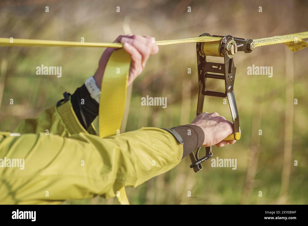 Gros plan mains d'Un homme ajuste le slackline de l'équipement avant d'effectuer des tours de slackline folles et de marcher sur un slacklin dans un parc dans le nat Banque D'Images