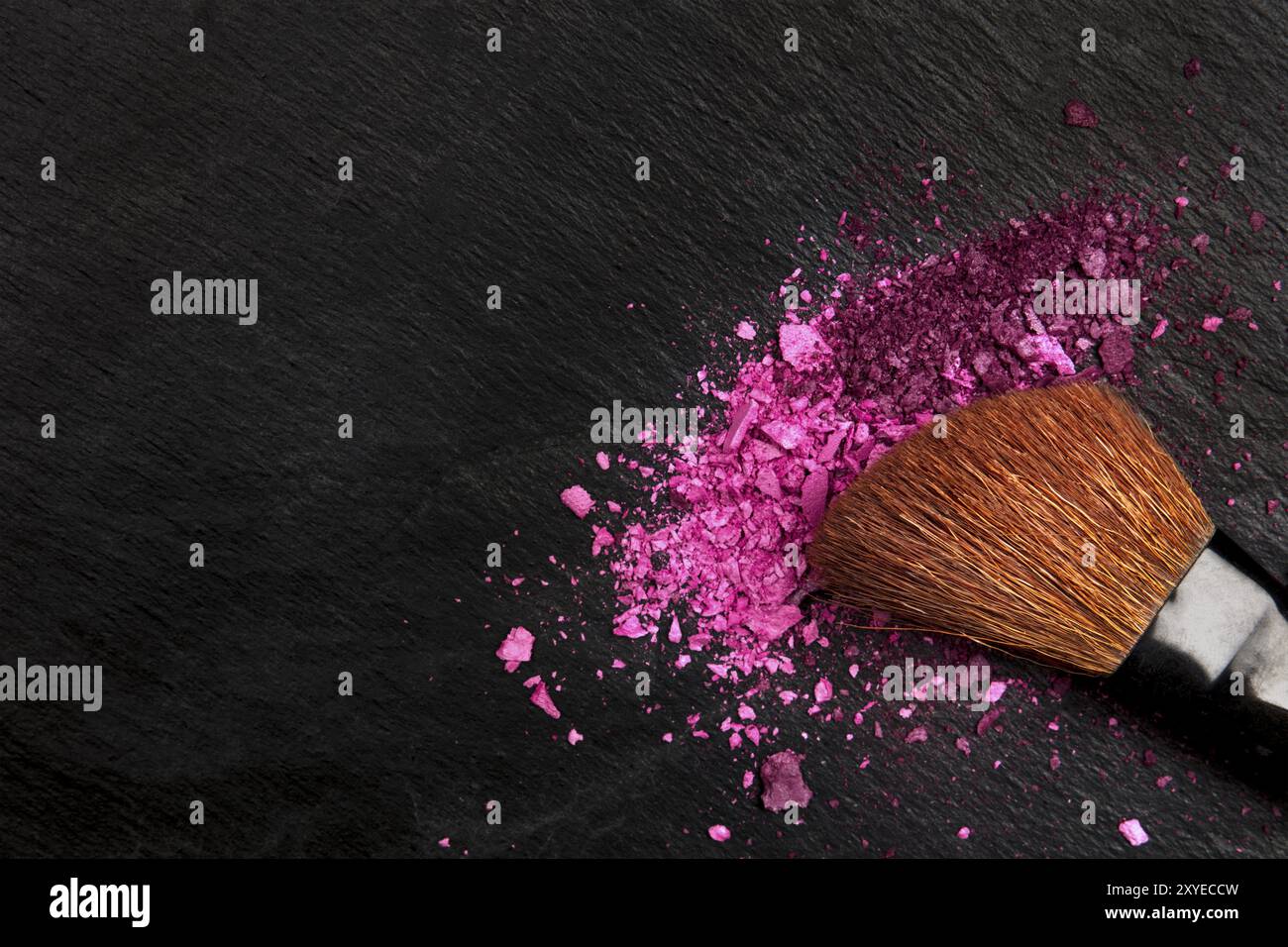 Un gros plan d'une brosse de maquillage aux couleurs rose et violet l'ombre d'oeil, tourné à partir de ci-dessus sur une texture noire with copy space Banque D'Images