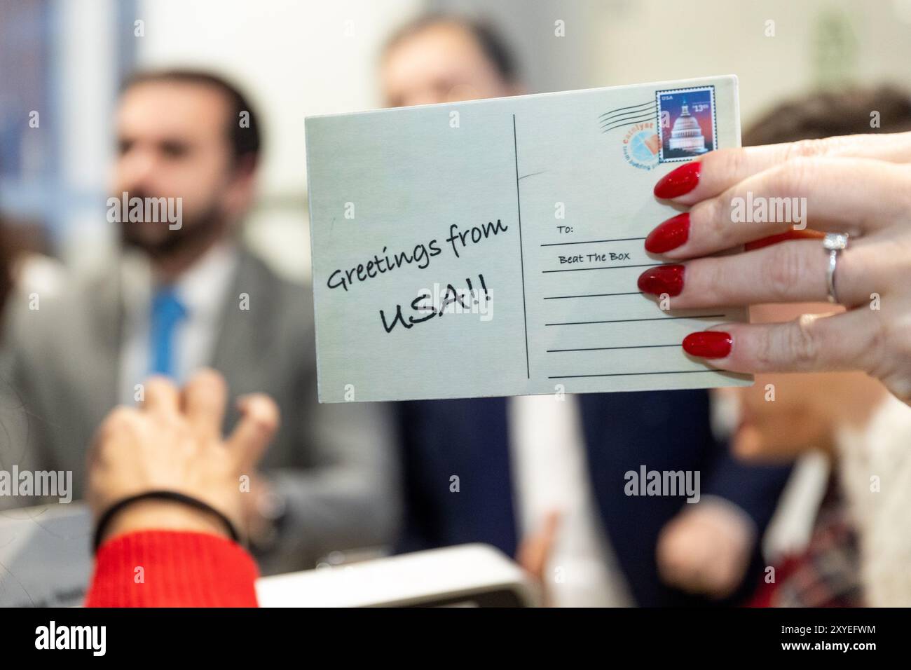 Main d'une femme tenant une carte postale disant 'salutations des USA'. Banque D'Images
