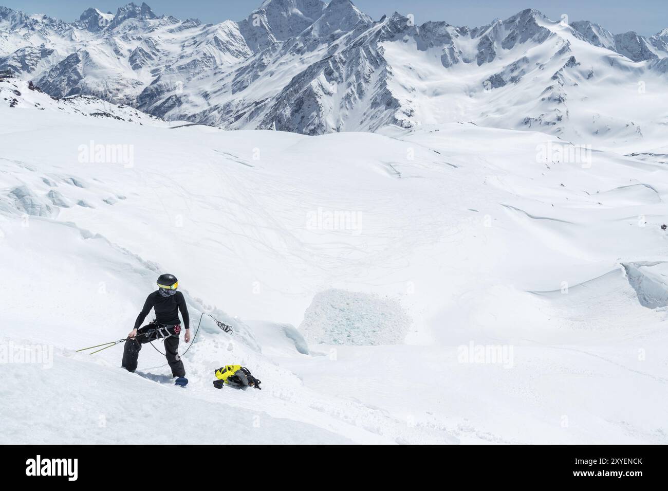 Un alpiniste professionnel portant un casque et un masque de ski sur l'assurance entaille la hache de glace dans le glacier. Le travail d'un grimpeur professionnel en Winte Banque D'Images