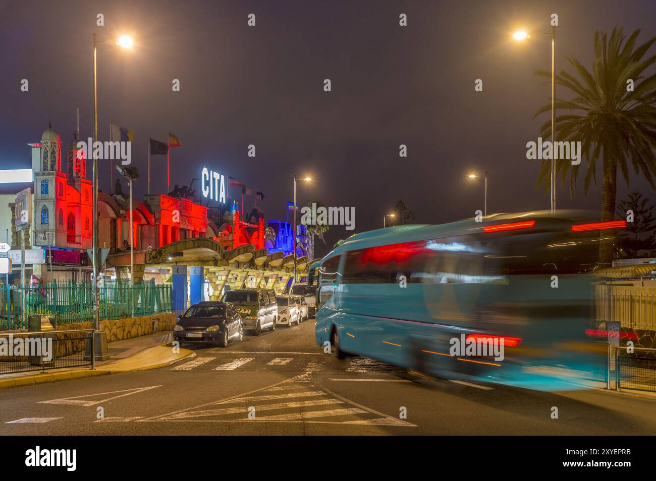 Prise de vue nocturne. Un autocar quitte un rond-point devant un centre commercial Banque D'Images