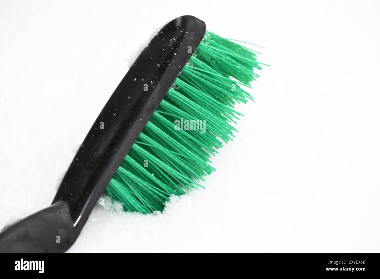 Brosse à main avec des poils verts dans la neige Banque D'Images