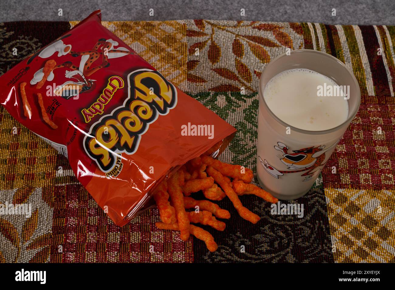 Cheetos croquant avec un verre de lait. Charles Elmer Doolin a inventé Cheetos en 1948, Frito-Lay est une filiale de PepsiCo. Chester Cheetah-Mascot!! Banque D'Images