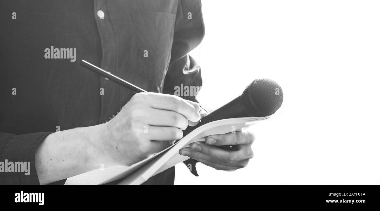 Cut-out d'un journaliste mâle dans un maillot bleu lors d'une conférence de presse qui est la prise de notes et la tenue d'un microphone Banque D'Images Cut-out d'un journaliste mâle dans un maillot bleu lors d'une conférence de presse qui est la prise de notes et la tenue d'un microphone Banque D'Images