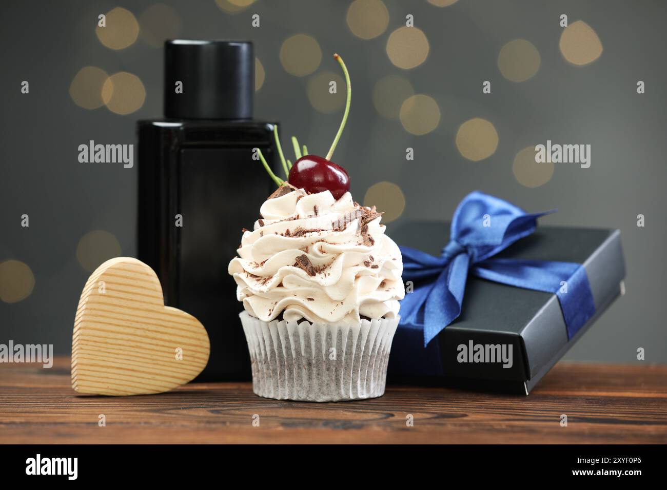 Bonne fête des pères. Cupcake, coffret cadeau, coeur en bois et parfum sur table contre les lumières floues Banque D'Images