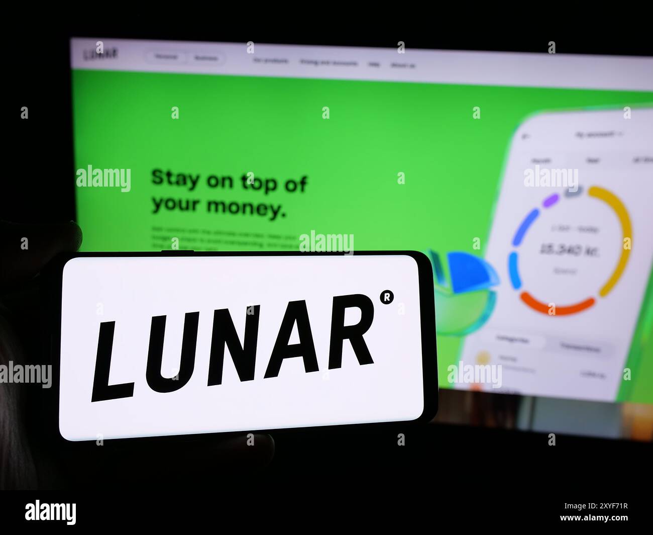 Personne tenant le smartphone avec le logo de la société danoise Fintech Lunar Bank COMME en face du site Web. Concentrez-vous sur l'affichage du téléphone. Banque D'Images