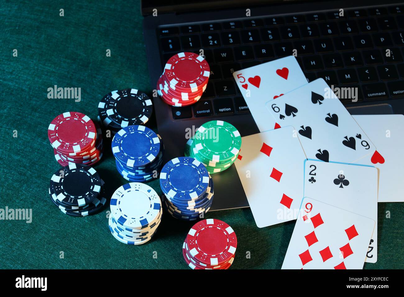 Poker en ligne. Cartes à jouer, jetons et ordinateur portable sur la table verte Banque D'Images