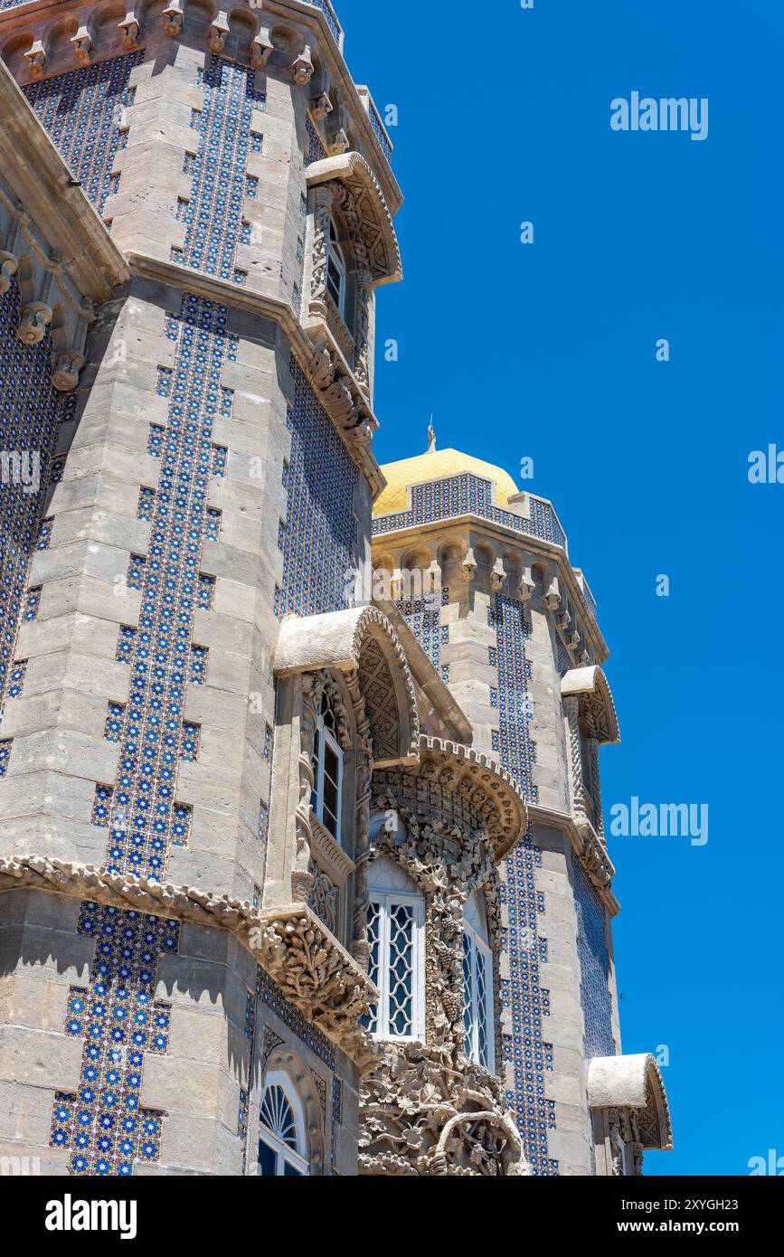 SINTRA, Portugal — L'architecture extérieure vibrante et éclectique du Palais de Pena, mettant en valeur son mélange de styles romantiste, mauresque et néo-manuélin. Les façades colorées du palais, les détails ornés et les éléments fantaisistes incarnent l'architecture romantique du XIXe siècle et la vision du roi Ferdinand II d'un château de conte de fées. Banque D'Images