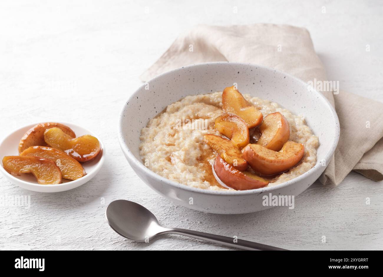 Bouillie d'avoine sucrée avec tranches de pomme cuites au four, cannelle et sauce caramel dans un bol gris sur un fond clair, vue de dessus. Délicieuse cuisine maison Banque D'Images