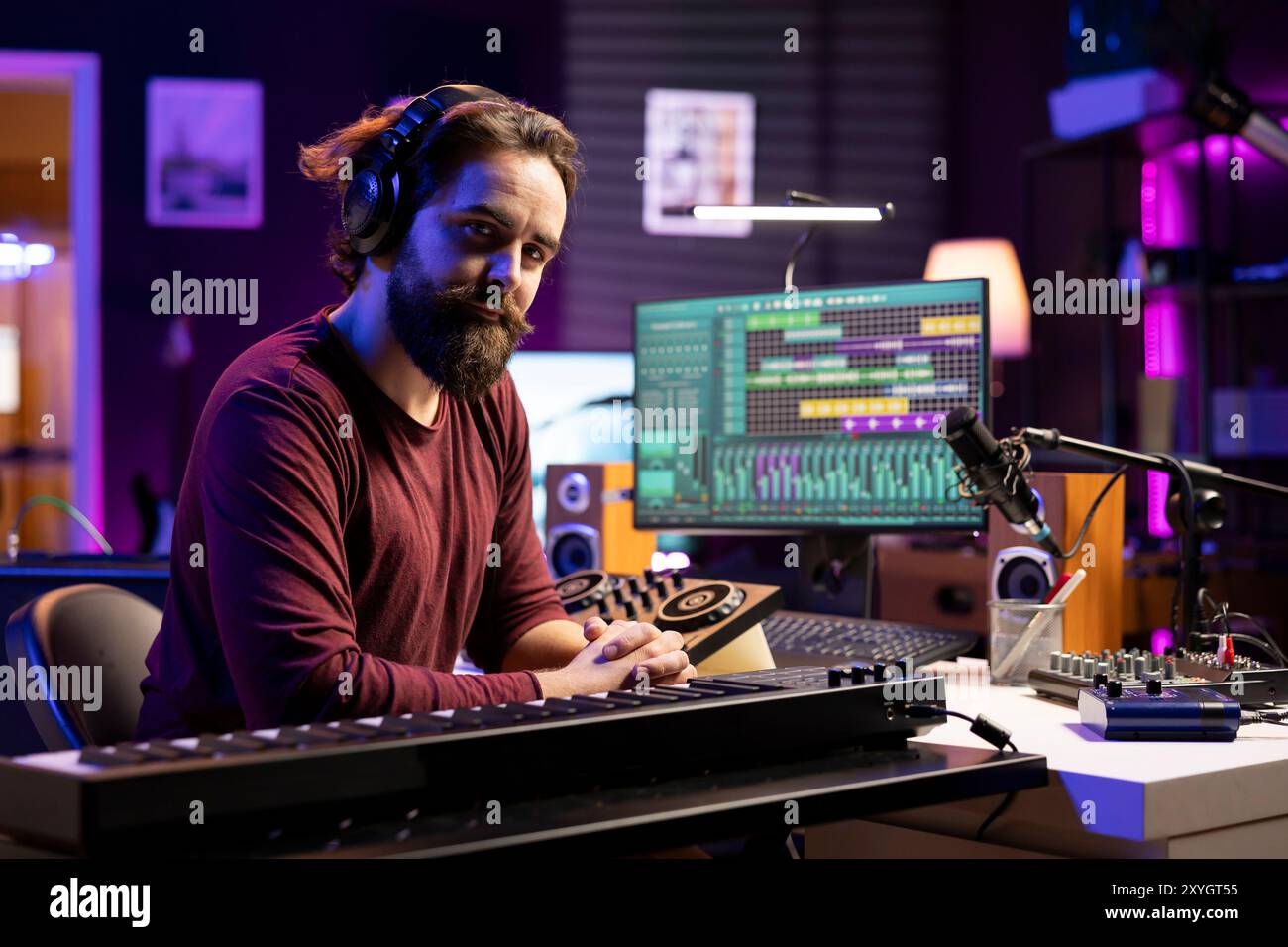 Portrait de l'artiste producteur jouant des notes de contrôleur midi et les ajoutant sur une nouvelle chanson, en utilisant l'interface du logiciel daw pour mixer et maîtriser les airs. Musicien qualifié créant de la musique avec des touches de piano. Banque D'Images