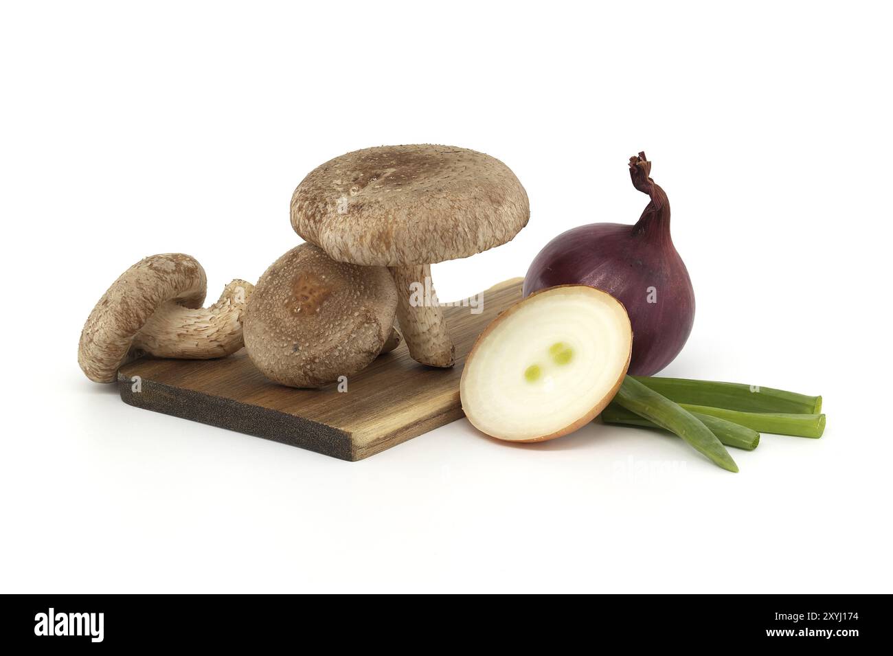 Champignons shiitake et divers oignons sur une planche à découper en bois isolée sur fond blanc. Recettes et herbes médicinales Banque D'Images