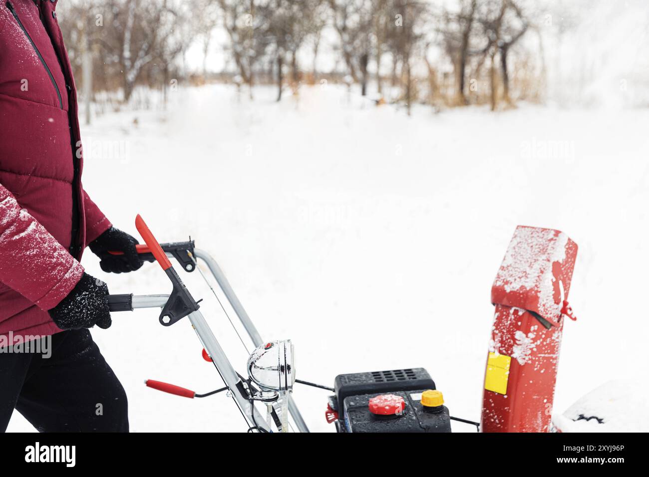 Détail de la souffleuse à neige rouge portable alimentée par l'essence en action. Homme à l'extérieur utilisant une souffleuse à neige après une tempête de neige. Déneigement, assistance pour fraise Banque D'Images