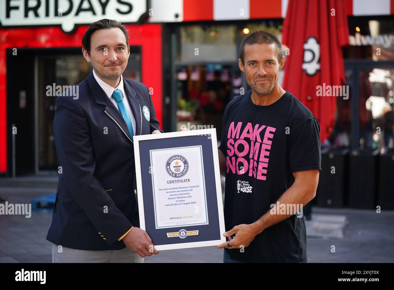 Will Munford (à gauche), arbitre du Guiness World Record, présente à Spencer Matthews, devant les écrans de Global LSQ à Londres, un certificat Guinness World Record après avoir terminé un défi de 30 marathons en 30 jours, en aide à Make Some Noise de Global. Date de la photo : vendredi 30 août 2024. Banque D'Images