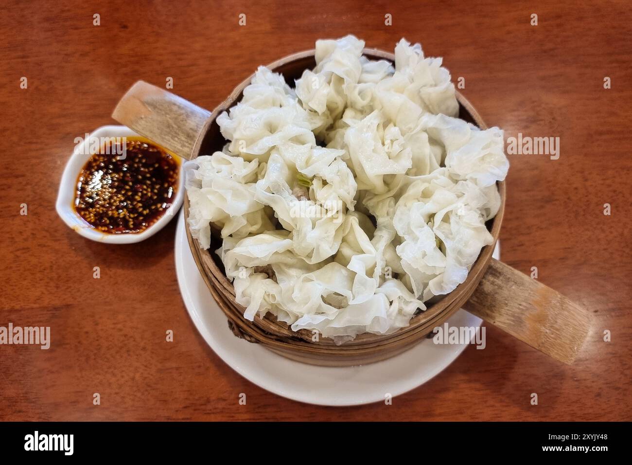 Populaire boulette chinoise Leshan ou jiaozi dans le vapeur de bambou et avec de l'huile de Chili comme trempettes. Banque D'Images