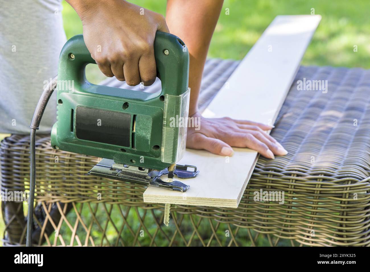 Le sciage femme planche en bois avec une scie sauteuse Électrique Banque D'Images