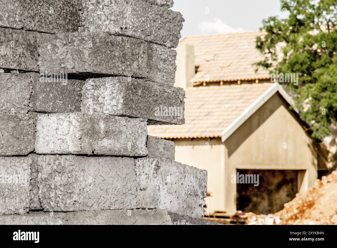 Vue rapprochée de briques de béton gris empilées devant une maison inachevée Banque D'Images