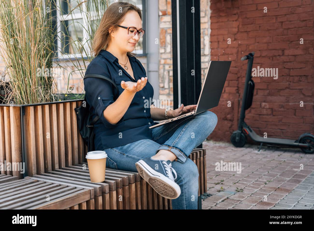 femme dans des lunettes s'engageant dans un appel vidéo ou une diffusion en direct à l'extérieur Banque D'Images