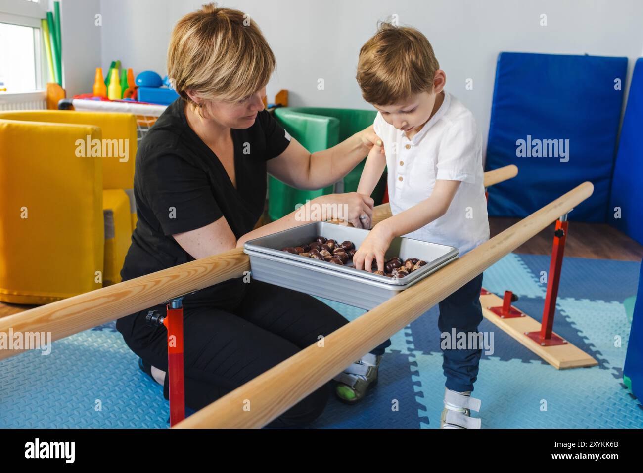 Le jeune garçon atteint de paralysie cérébrale participe à une activité thérapeutique et physique avec le soutien d’un physiothérapeute dans un espace de réadaptation Banque D'Images