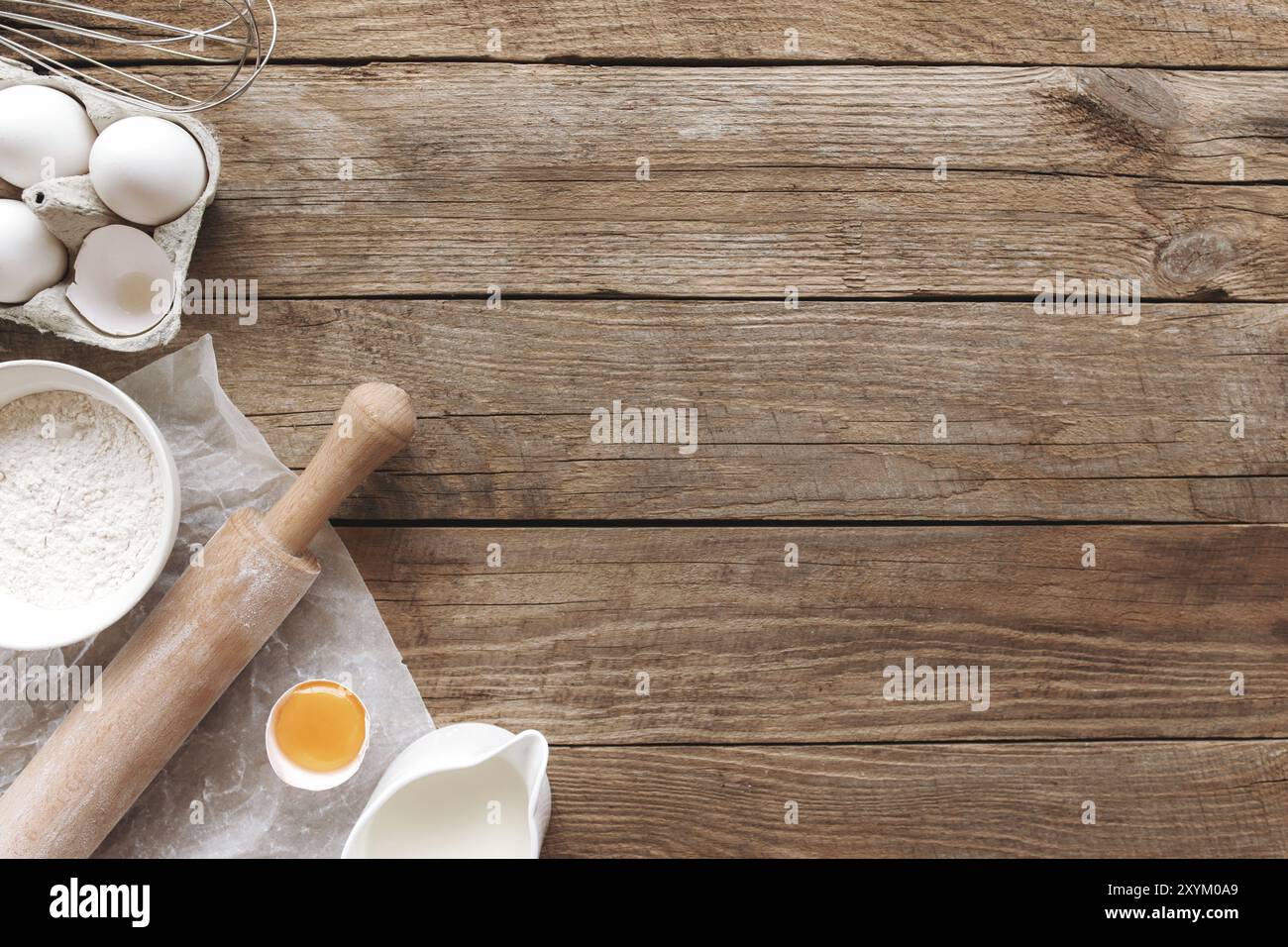 Ingrédients de cuisson, ustensiles de cuisine sur fond de bois ancien.Pâte à cuire, préparation du jaune d'œuf, farine, rollPIN, lait,papier parchemin, fouet, sa Banque D'Images