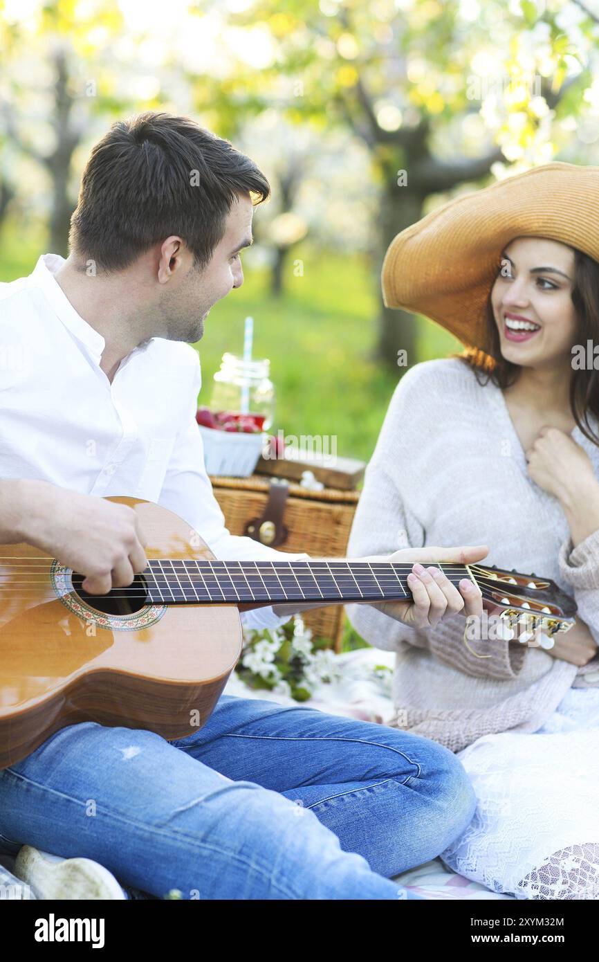 Jeune couple amoureux au pique-nique dans le jardin en fleurs au printemps. Concept de bonheur et d'amour Banque D'Images