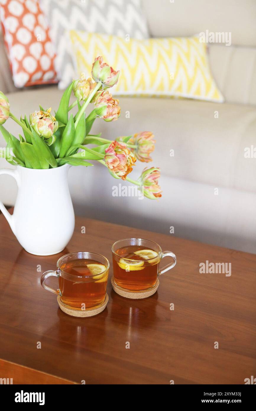 Beau bouquet de tulipes orange avec deux tasses de thé sur la table en bois dans le salon Banque D'Images