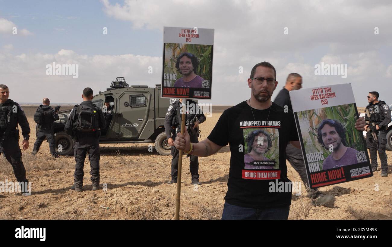 NIRIM, ISRAËL - AOÛT 29 : le cousin d'Ofer Kalderon, 53 ans, qui est retenu en otage à Gaza se tient debout avec des affiches portant sa photo alors que des membres des forces de sécurité israéliennes empêchent des proches d'otages israéliens enlevés le 7 octobre par le Hamas de marcher vers Gaza après avoir utilisé des haut-parleurs géants pour appeler leurs proches captifs près de la frontière avec la bande de Gaza le 29 août 2024 au Kibboutz Nirim, en Israël. Le Hamas a saisi environ 250 Israéliens et étrangers lors de ses attaques du 7 octobre contre le sud d’Israël, dont 108 sont toujours en captivité. Banque D'Images NIRIM, ISRAËL - AOÛT 29 : le cousin d'Ofer Kalderon, 53 ans, qui est retenu en otage à Gaza se tient debout avec des affiches portant sa photo alors que des membres des forces de sécurité israéliennes empêchent des proches d'otages israéliens enlevés le 7 octobre par le Hamas de marcher vers Gaza après avoir utilisé des haut-parleurs géants pour appeler leurs proches captifs près de la frontière avec la bande de Gaza le 29 août 2024 au Kibboutz Nirim, en Israël. Le Hamas a saisi environ 250 Israéliens et étrangers lors de ses attaques du 7 octobre contre le sud d’Israël, dont 108 sont toujours en captivité. Banque D'Images