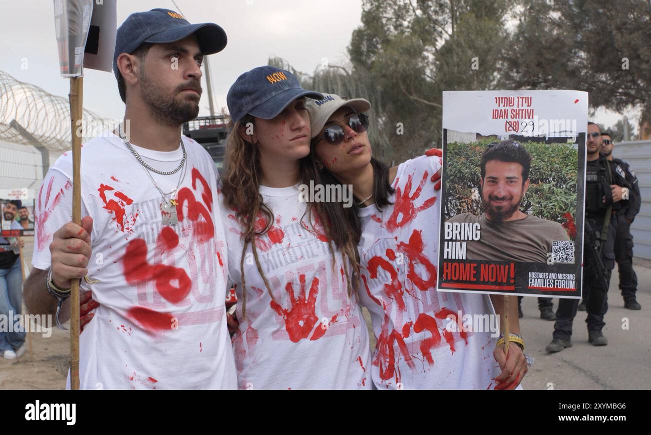 NIRIM, ISRAËL - AOÛT 29 : des proches d'Idan Shtivi, 28 ans, qui est retenu en otage à Gaza, se tiennent debout avec une affiche portant sa photo, tandis que les membres de la famille utilisent des haut-parleurs géants pour appeler leurs proches captifs près de la frontière avec la bande de Gaza le 29 août 2024 au Kibboutz Nirim, Israël. Le Hamas a saisi environ 250 Israéliens et étrangers lors de ses attaques du 7 octobre contre le sud d’Israël, dont 108 sont toujours en captivité. Banque D'Images NIRIM, ISRAËL - AOÛT 29 : des proches d'Idan Shtivi, 28 ans, qui est retenu en otage à Gaza, se tiennent debout avec une affiche portant sa photo, tandis que les membres de la famille utilisent des haut-parleurs géants pour appeler leurs proches captifs près de la frontière avec la bande de Gaza le 29 août 2024 au Kibboutz Nirim, Israël. Le Hamas a saisi environ 250 Israéliens et étrangers lors de ses attaques du 7 octobre contre le sud d’Israël, dont 108 sont toujours en captivité. Banque D'Images