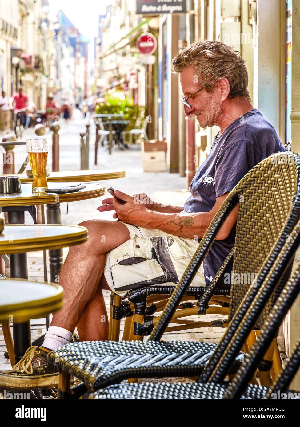 Homme d'âge moyen (travailleur) à la table de café en plein air regardant smartphone - Tours, Indre-et-Loire (37), France. Banque D'Images
