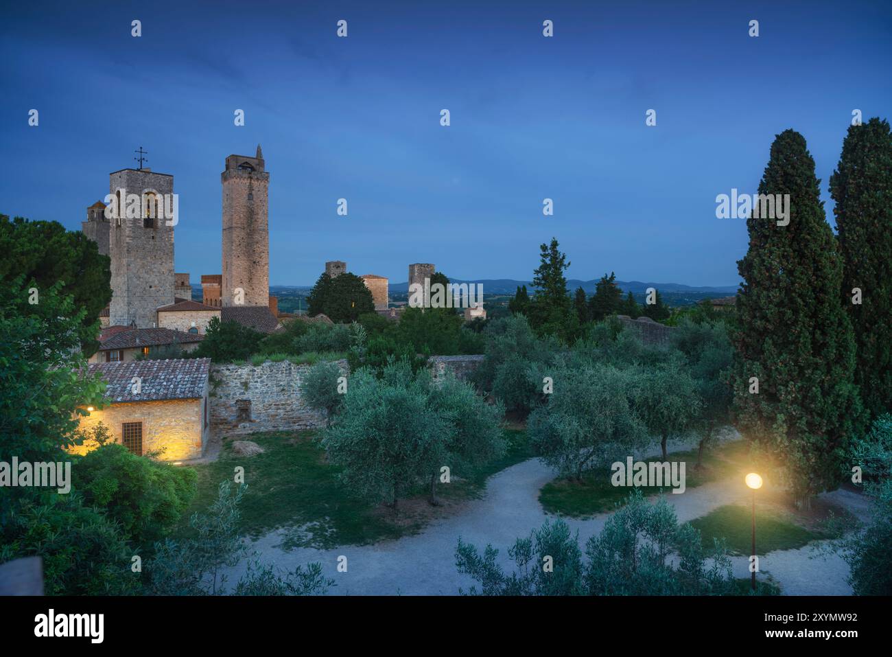 Vue nocturne de San Gimignano avec ses tours depuis un parc public avec des oliviers. Province de Sienne, région Toscane, Italie Banque D'Images