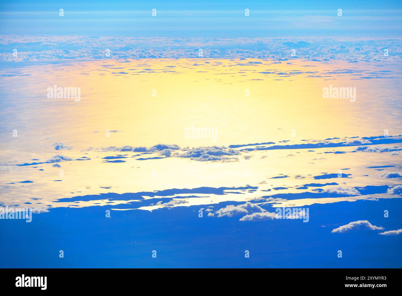 Vue aérienne montrant le vaste océan rencontrant le ciel, capturée depuis une fenêtre d'avion pendant le vol. Survoler les nuages et l'océan au crépuscule Banque D'Images