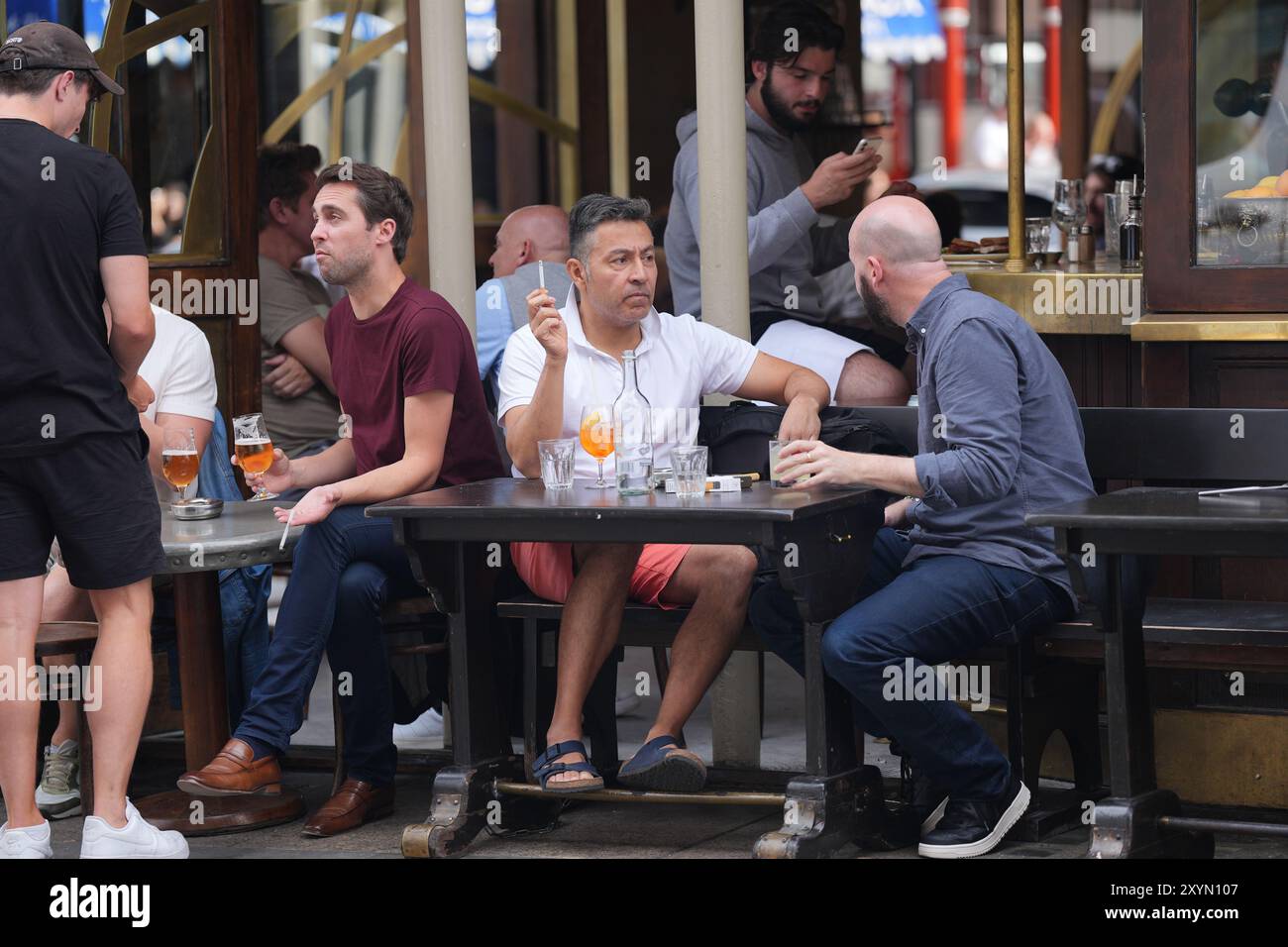 Une personne fume une cigarette alors qu'elle est assise à l'extérieur dans un pub, à Soho, Londres. Le premier ministre britannique Keir Starmer a déclaré qu'il n'avait pas exclu une interdiction de fumer dans les espaces extérieurs tels que les jardins de pub, les campus d'hôpitaux et d'universités, les aires de jeux pour enfants et les terrains de sport, lorsqu'on lui a demandé de fumer jeudi. Date de la photo : vendredi 30 août 2024. Banque D'Images