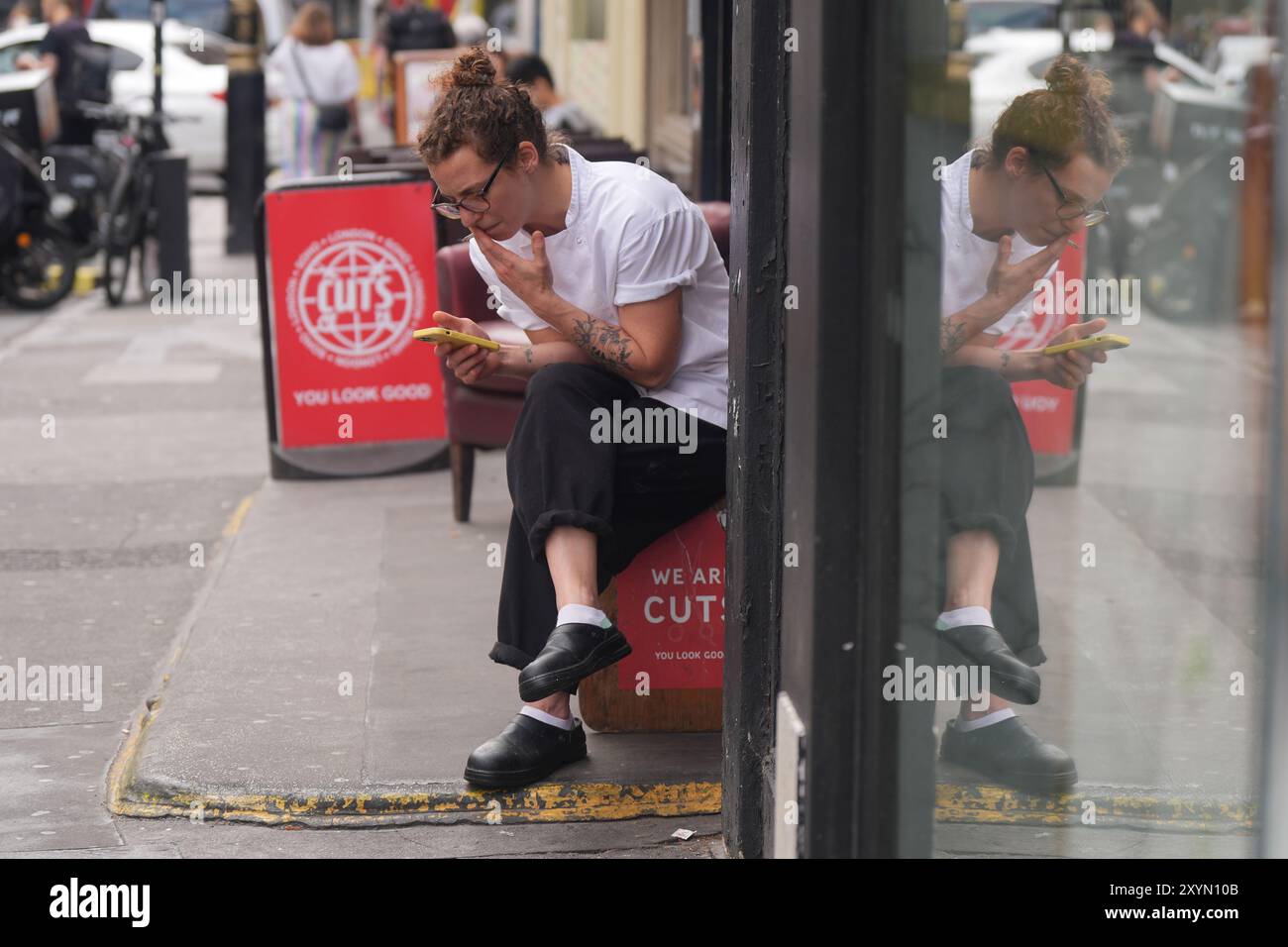 Un ouvrier fumant une cigarette à l'extérieur à Soho, Londres. Le premier ministre britannique Keir Starmer a déclaré qu'il n'avait pas exclu une interdiction de fumer dans les espaces extérieurs tels que les jardins de pub, les campus d'hôpitaux et d'universités, les aires de jeux pour enfants et les terrains de sport, lorsqu'on lui a demandé de fumer jeudi. Date de la photo : vendredi 30 août 2024. Banque D'Images