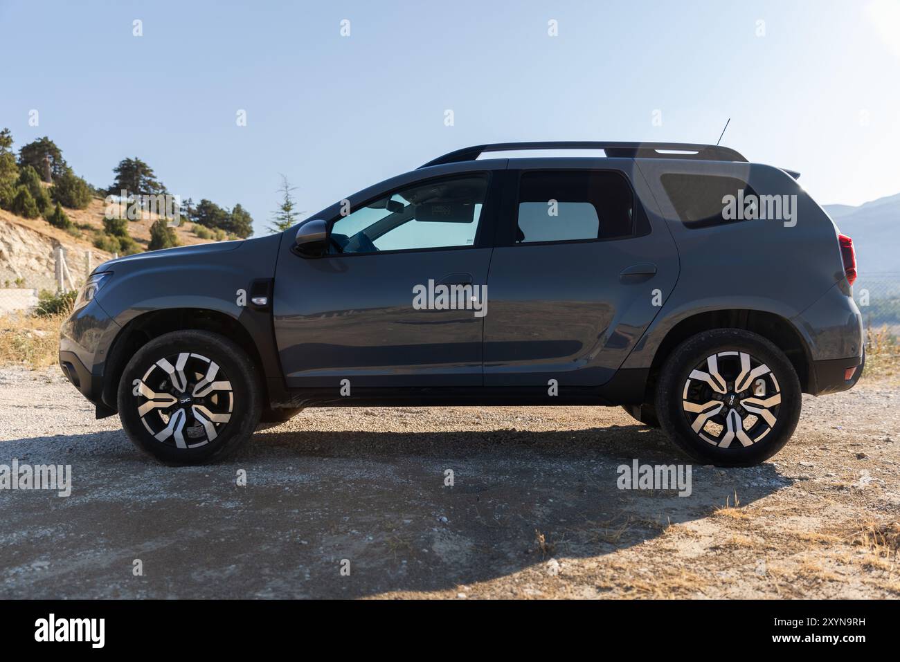 Kalkan, Turquie - 13 août 2024 : 2024 Dacia Duster vue latérale. Véhicule tout-terrain gris moderne se dresse sur le bord de la route près de la route de montagne sur un summe ensoleillé Banque D'Images