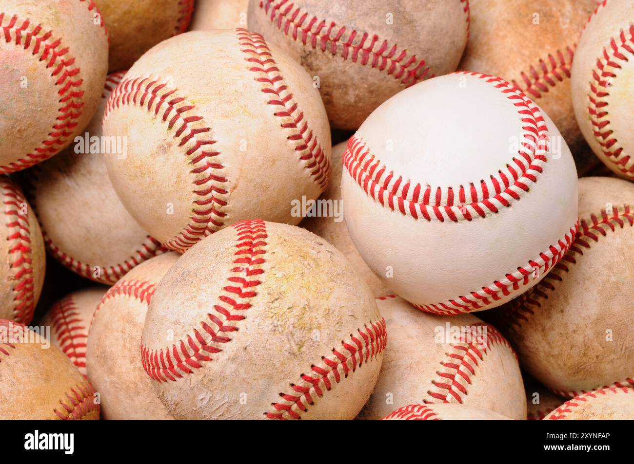 Gros plan d'une pile de vieilles balles de baseball usagées avec une nouvelle balle au milieu. Format horizontal. Banque D'Images