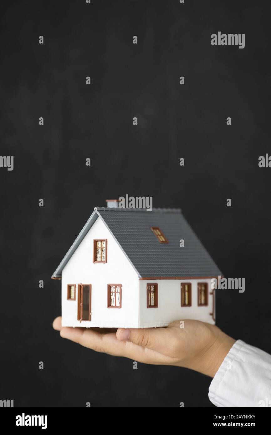 Nouvelle maison dans les mains contre tableau noir blanc Banque D'Images