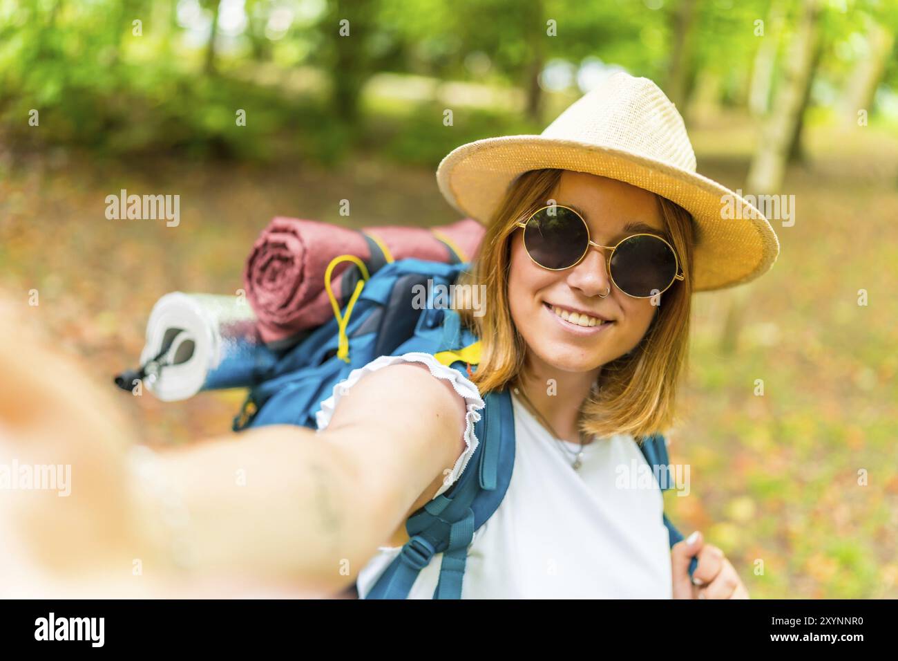 Une jeune aventurière voyageant le long d'une forêt dans les bois et prenant un selfie avec son téléphone Banque D'Images