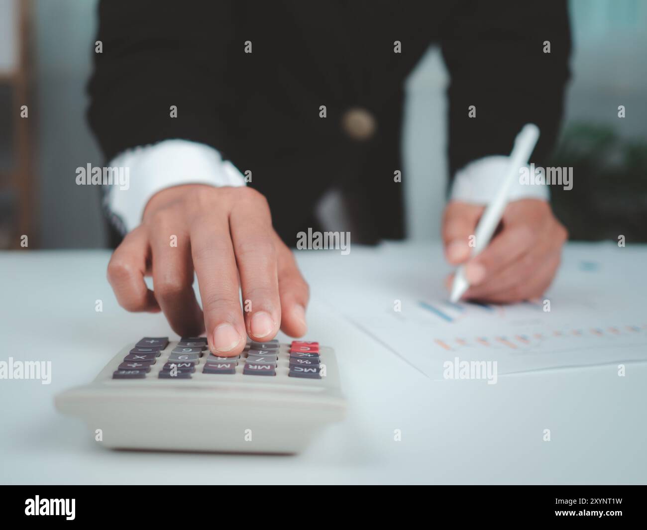 Femme d'affaires en costume noir travaillant sur ordinateur portable et tablette et calculatrice, mains toucher sur tablette au bureau avec fond sombre, WO en ligne Banque D'Images