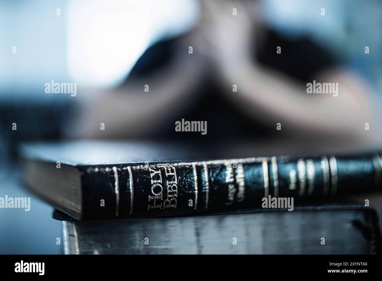 Gros plan de la Bible en cuir avec des mots de la Bible Sainte en Focused, homme priant en arrière-plan Bokeh Banque D'Images