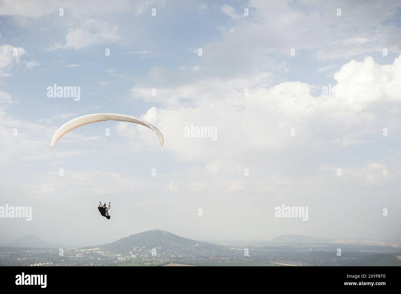 Un parapente blanc-orange survole le terrain montagneux Banque D'Images